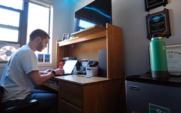 Joe in townhouse dorm at desk on laptop