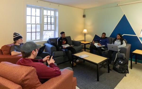 Students in common space in dorm talking and working