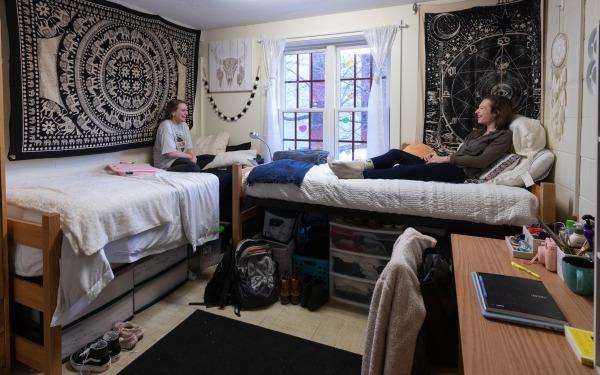 Female students talking on beds in fully decorated dorm room
